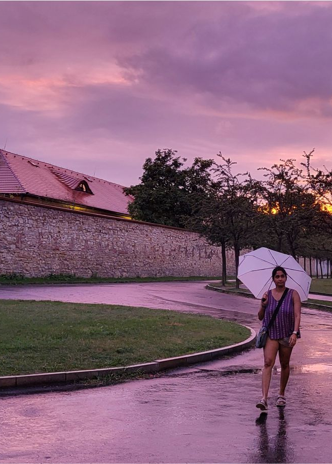 A woman holding a white umbrella in a calm, scenic setting, representing focus and clarity in how Ideas to Reach approaches digital marketing services.